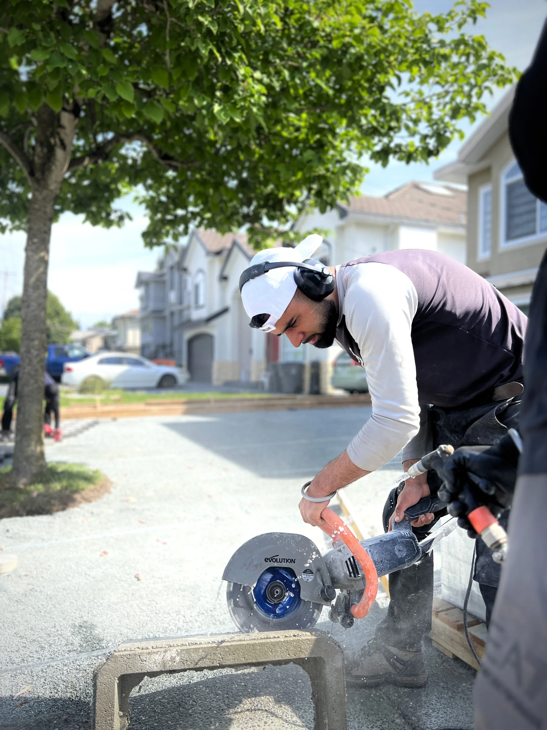 A Country West Construction crew member cutting paving stone on a residential job site in the Lower Mainland.