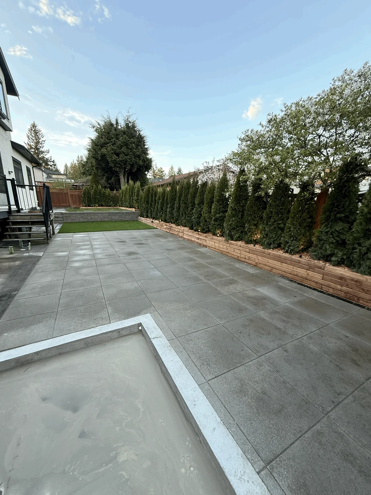 Paved patio and retaining wall alongside the finished back yard lawn.