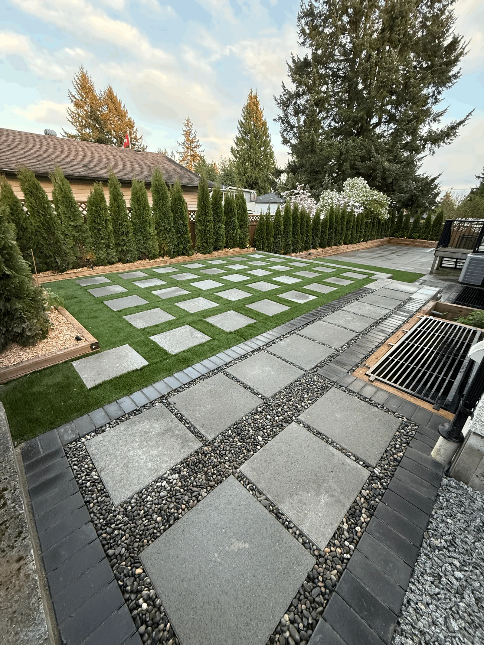 Backyard lawn with a grid of square concrete pavers set into the turf.